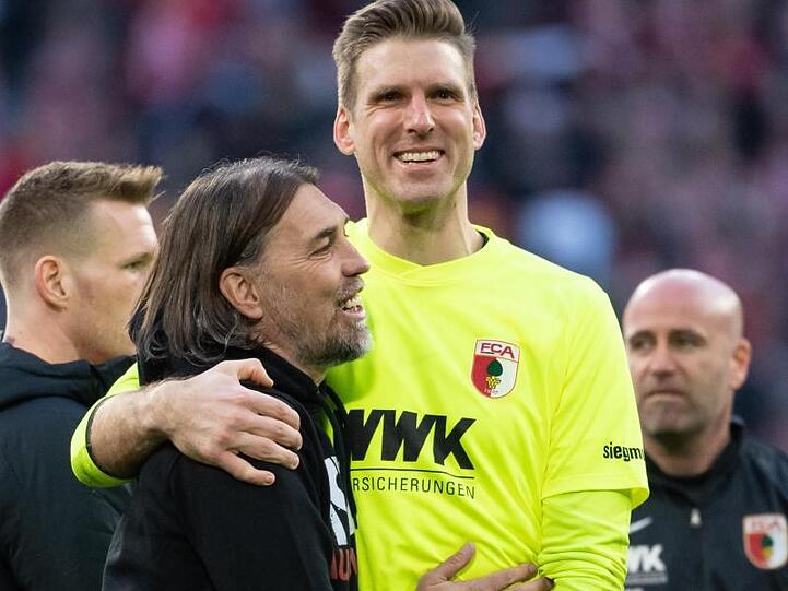 Trainer Martin Schmidt (l.) von Augsburg und Torwart Andreas Luthe klatschen sich nach dem Spiel ab. Foto: Sven Hoppe/dpa