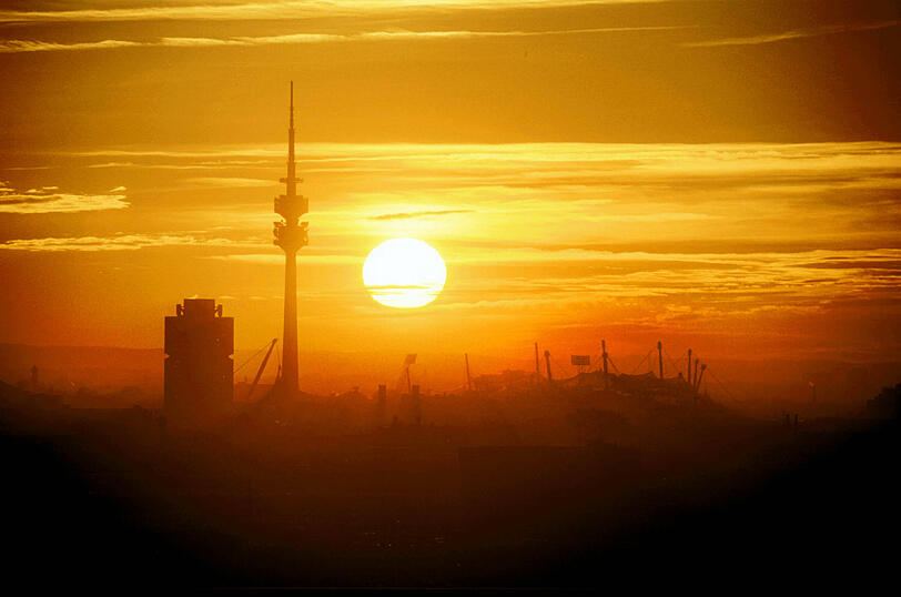 Sahara-Staub beim Sonnenaufgang über München: BMW-Turm, Olympiaturm und Olympiastadion.