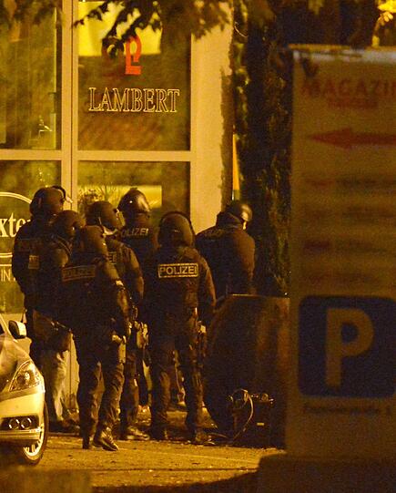 Mit erhobenen Händen kommt ein Mann auf die SEK-Beamten zu, im Hintergrund lauern Heckenschützen der Polizei. Die Beamten nehmen den Mann fest, es ist aber nicht der Täter, der sich in einem Imbiss in Freiburg veschanzt hat.