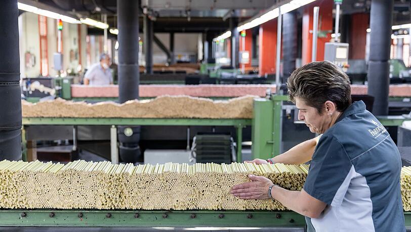 Eine Mitarbeiterin des Schreibwaren-Herstellers plaziert in der Buntstift-Lackierung Stifte auf einem Förderband.
