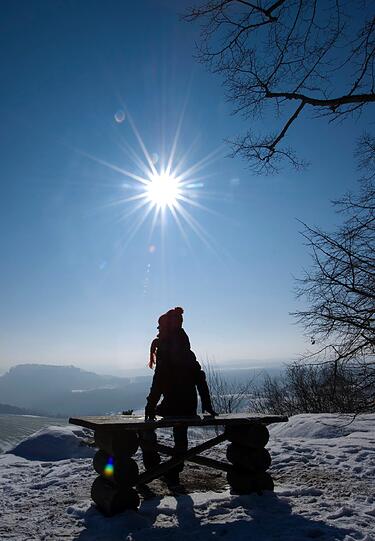 Eine Spaziergängerin schaut während einer Wanderung von dem Tafelberg "Kleiner Bärenstein" bei Naundorf über die Landschaft der Sächsischen Schweiz. Laut Wettervorhersage soll auch in den kommenden Tagen die Sonne scheinen, auch die Temperaturen bleiben weiterhin weit unter dem Gefrierpunkt.