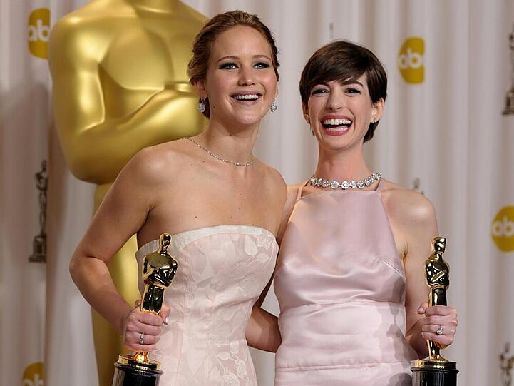 Strahlende Siegerinnen mit ihren Goldjungen: Jennifer Lawrence (l.) und Anne Hathaway (r.)