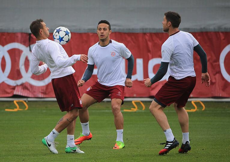 Rafinha, das Geburtstagskind Thiago und Xabi Alonso halten den Ball in der Luft.