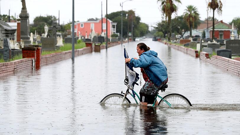 Ein massives Hochwasser sucht den US-Bundesstaat Texas im September heim. Hier radelt in Galveston eine Frau durch die Flut am Broadway Cemetery Historic District.