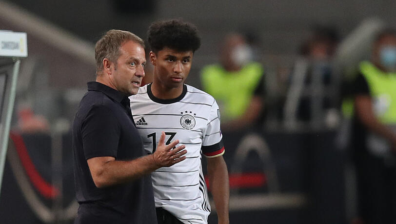 Trainer Hansi Flick (l) bespricht sich mit Karim Adeyemi vor dessen Einwechslung.