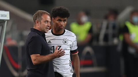 Trainer Hansi Flick (l) bespricht sich mit Karim Adeyemi vor dessen Einwechslung.