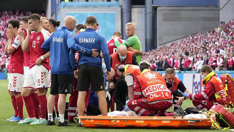 Christian Eriksen von Dänemark (auf dem Boden) wird medizinisch behandelt. Er war auf dem Rasen zusammengebrochen, sofort herbeigerufene Helfer führten lebensrettende Maßnahmen aus. Christian Eriksen von Dänemark (auf dem Boden) wird medizinisch behandelt. Er war auf dem Rasen zusammengebrochen, sofort herbeigerufene Helfer führten lebensrettende Maßnahmen aus.