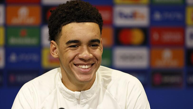 Jamal Musiala vom FC Bayern lächelt während einer Pressekonferenz.