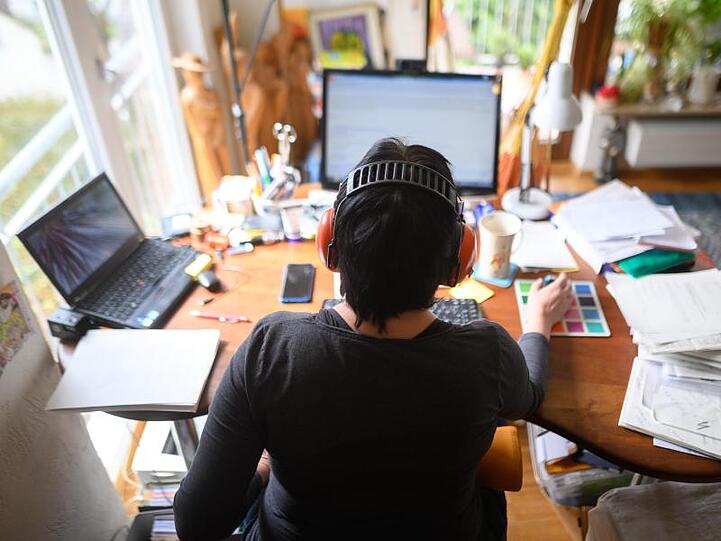 Eine Frau arbeitet mit Hörschutz im Homeoffice.