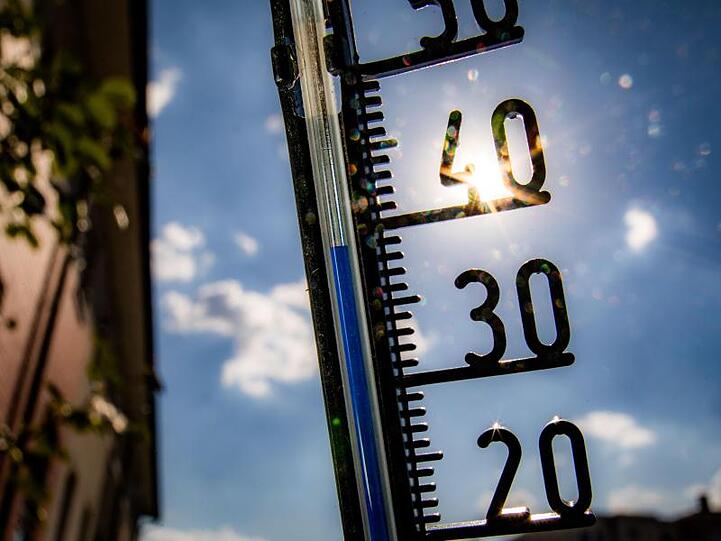 Ein Thermometer klettert bei praller Sonne in Richtung der 40-Grad-Marke. Foto: Frank Rumpenhorst/dpa/Symbolbild