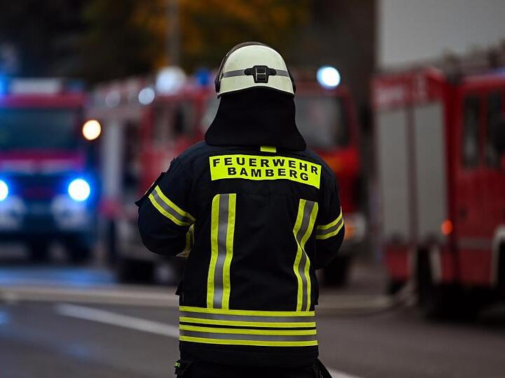 Ein Feuerwehrmann steht bei Nachlöscharbeiten vor mehreren Feuerwehreinsatzfahrzeugen. Foto: Nicolas Armer/dpa/Archivbild