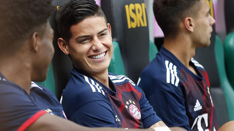Neuzugang James Rodriguez sitzt zunächst noch auf der Bank. Lächelnd blickt er seiner Premiere im Bayern-Trikot entgegen.