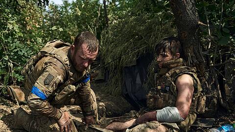 Ein ukrainischer Soldat leistet seinem verwundeten Kameraden erste Hilfe.