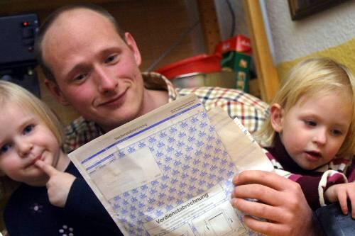 Ein Familienvater mustert seine Gehaltsabrechnung: Ab März steht netto mehr drauf.