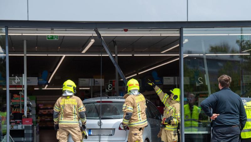 Feuerwehrmänner schneiden ein Auto aus der Glasfront eines Supermarkts. Foto: Lino Mirgeler Feuerwehrmänner schneiden ein Auto aus der Glasfront eines Supermarkts. Foto: Lino Mirgeler