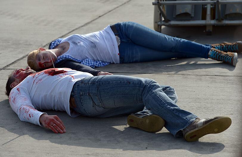 Während einer Großübung am Flughafen in Hannover (Niedersachsen) liegen nach einem simulierten Flugzeugabsturz am 10.05.2014 zwei als verletzte Passagiere geschminkte Darsteller auf dem Boden. Die Feuerwehr, Polizei und andere Rettungsorganisationen trainieren während einer Großübung am Flughafen die Zusammenarbeit. Foto: Peter Steffen/dpa