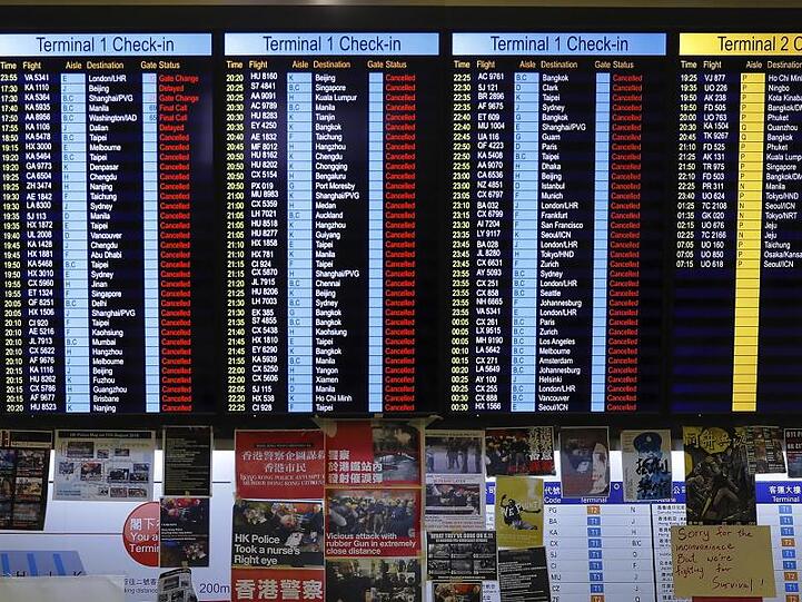 Plakate von Demonstranten unter der Fluginformationstafel des Airports.