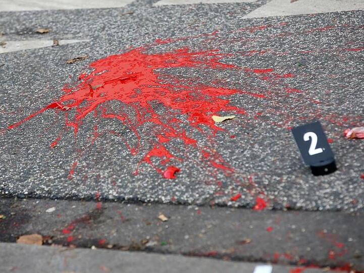 Farbe und Glasscherben liegen auf einer Straße hinter einer Polizeiabsperrung.