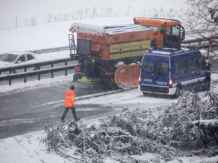 Ein Fahrzeug vom Winterdienst fährt durch eine Engstelle, an der Bäume am Straßenrand umgefallen sind. Foto: Bernd März