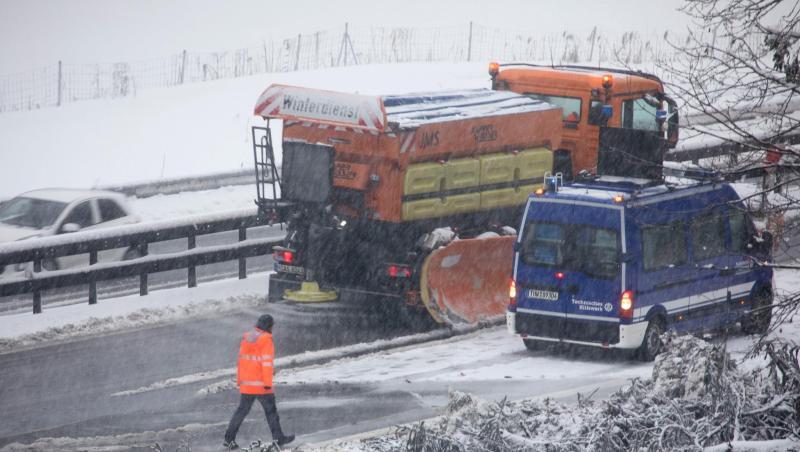 Ein Fahrzeug vom Winterdienst fährt durch eine Engstelle, an der Bäume am Straßenrand umgefallen sind. Foto: Bernd März