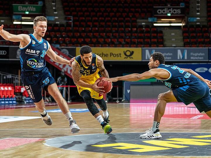 Martin Hermannsson (l) und Kenneth Ogbe (r) von Alba Berlin verteidigen gegen Oldenburgs Tyler Larson.