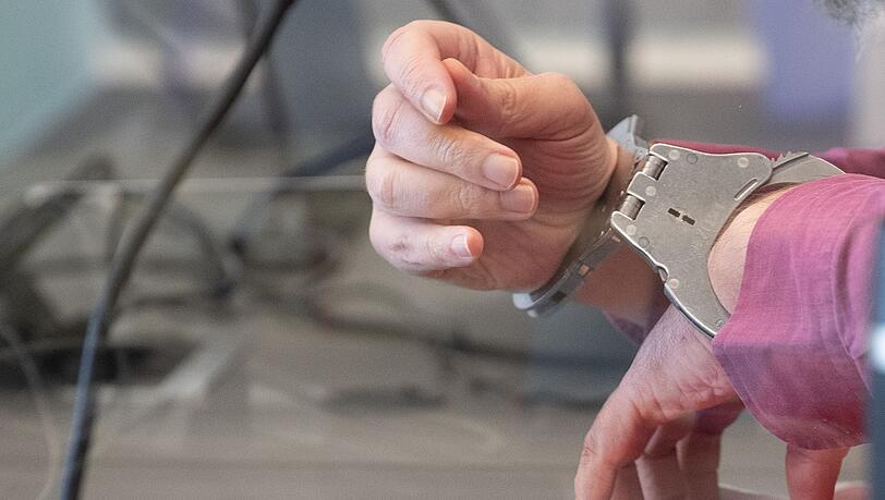Der Angeklagte sitzt mit Handschellen im Gerichtssaal.