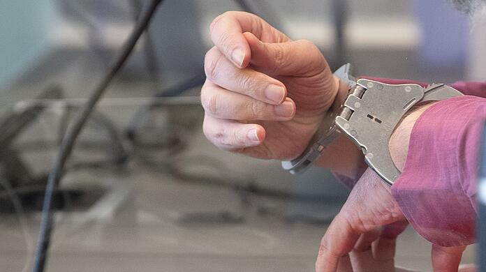 Der Angeklagte sitzt mit Handschellen im Gerichtssaal.