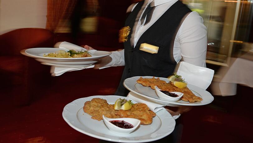 Eine Bedienung serviert in einem Restaurant in Hinterzarten Teller mit Schnitzeln. Für guten Service zehn Prozent draufzuzahlen, gilt in der Branche als üblich.