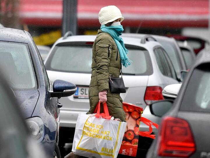 Eine Frau mit Mundschutz auf dem Parkplatz eines Einkaufszentrums in Salzburg.