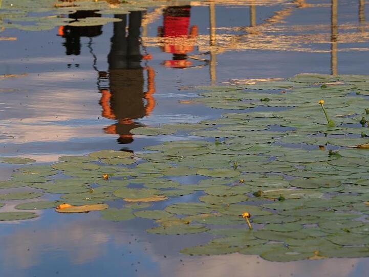Ausflügler spiegeln sich auf dem Wasser des Hopfensees. Foto: