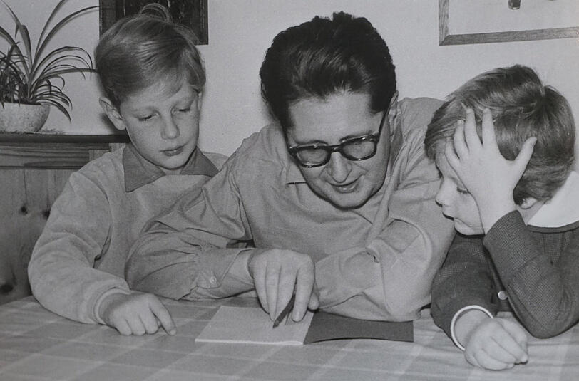 Bei der Abendlektüre mit den Kindern: Das muss um 1960 herum gewesen sein. Da studiere ich gerade irgendwas mit meinen beiden Ältesten, dem Bernd und der Sabine. Was wir da genau angeschaut haben, weiß ich nicht mehr. So weit mir das zeitlich möglich war, habe ich jedenfalls sehr gerne Zeit mit meinen Kindern verbracht. Ich dürfte auf dem Bild ja schon Oberbürgermeister gewesen sein &ndash; oder zumindest berufsmäßger Stadtrat. In der Partei war ich damals auch schon sehr aktiv. Da blieb nicht immer so viel Zeit, wie man sich das gewünscht hätte. Wir haben auch Wanderungen in die Berge unternommen. Manchmal habe ich auch aus einem alten Kinderbuch vorgelesen, das konnte ich fast auswendig. &bdquo;Der Osterhas&rsquo; auf Reisen&ldquo;, hieß das. &bdquo;Was mach&rsquo; ich nur die lange Frist, bis wieder einmal Ostern ist? Ach, rief er da mit hellem Lachen, ich werde eine Reise machen. Gesagt, getan, ein Mann, ein Wort. Am selben Tag fuhr er noch fort.&ldquo; So ging das &ndash; und ich kann&rsquo;s noch immer.