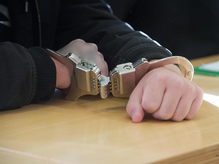Ein Mann in Handschellen sitzt an einem Tisch. Foto: Stefan Sauer/zb/dpa/Archivbild