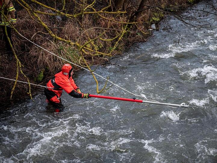 Feuerwehrleute versuchen, einen Gegenstand aus dem Fluss zu bergen.
