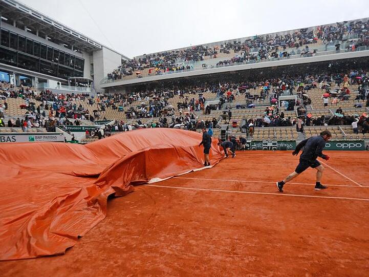 Mitarbeiter decken den Center Court ab, nachdem das Halbfinale wegen Regens unterbrochen wurde.
