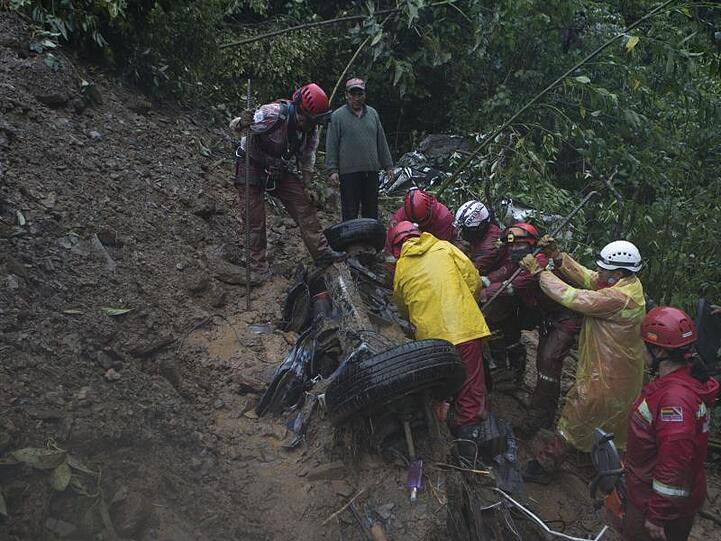 Feuerwehrleute versuchen nach einer Schlammlawine in Bolivien Opfer aus einem Auto zu retten.