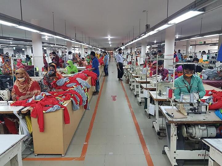 In einer Textilfabrik im bangladeschischen Savar sitzen Näherinnen und Näher bei der Arbeit.