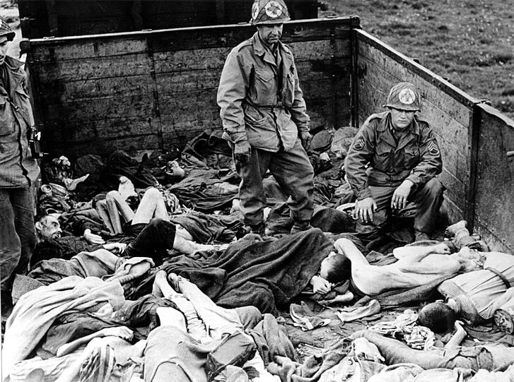 Fassungslose US-Soldaten stehen in Dachau auf einem Eisenbahnwaggon mit ermordeten Häftlin-en, die meisten von ihnen sind zu Skeletten abgemagert.