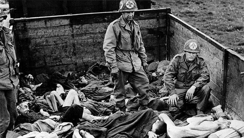 Fassungslose US-Soldaten stehen in Dachau auf einem Eisenbahnwaggon mit ermordeten Häftlin-en, die meisten von ihnen sind zu Skeletten abgemagert. Fassungslose US-Soldaten stehen in Dachau auf einem Eisenbahnwaggon mit ermordeten Häftlin-en, die meisten von ihnen sind zu Skeletten abgemagert.