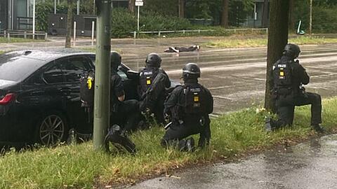 Der Tatverdächtige liegt vor dem Sozialbürgerhaus am Boden. Im Vordergrund knien schwer bewaffnete Polizisten mit Maschinenpistolen und Schutzausrüstung. Polizeipräsidium München Der Tatverdächtige liegt vor dem Sozialbürgerhaus am Boden. Im Vordergrund knien schwer bewaffnete Polizisten mit Maschinenpistolen und Schutzausrüstung. Polizeipräsidium München