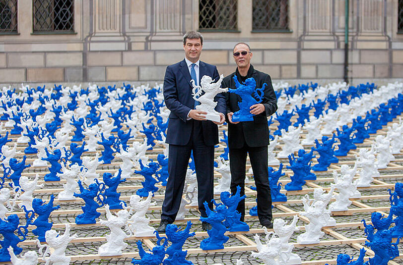 Der Bayerische Finanzminister Markus Söder (l) und Ottmar Hörl, der Präsident der Akademie der Bildenden Künste in Nürnberg stehen inmitten von 2000 weißen und blauen Kunststofflöwen im Kaiserhof der Residenz in München.