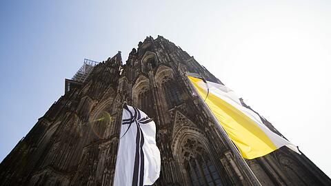 Vor dem Dom in Köln weht eine Flagge mit einem Kreuz und Trauerflor. Am Freitag findet hier der Trauergottesdienst für die Opfer des Absturzes des Germanwings Airbus in Frankreich statt.