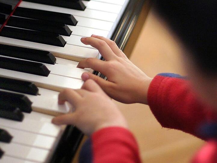 Ein Junge spielt an einem Flügel.