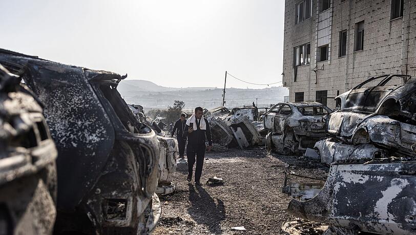 Männer gehen in Huwara an verbrannten und zerstörten Fahrzeugen vorbei. Nach einem tödlichen Anschlag auf zwei Israelis war es dort zu schweren Ausschreitungen israelischer Siedler gekommen.