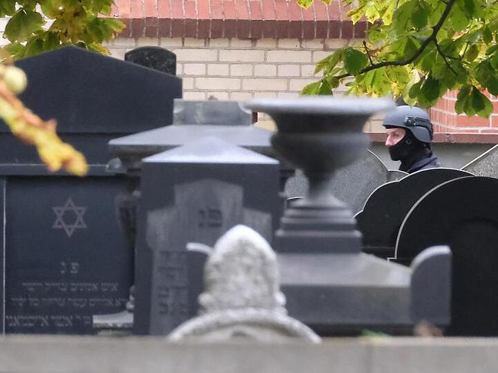 Ein Polizist mit Schutzhelm steht zwischen Grabsteinen auf dem jüdischen Friedhof von Halle.