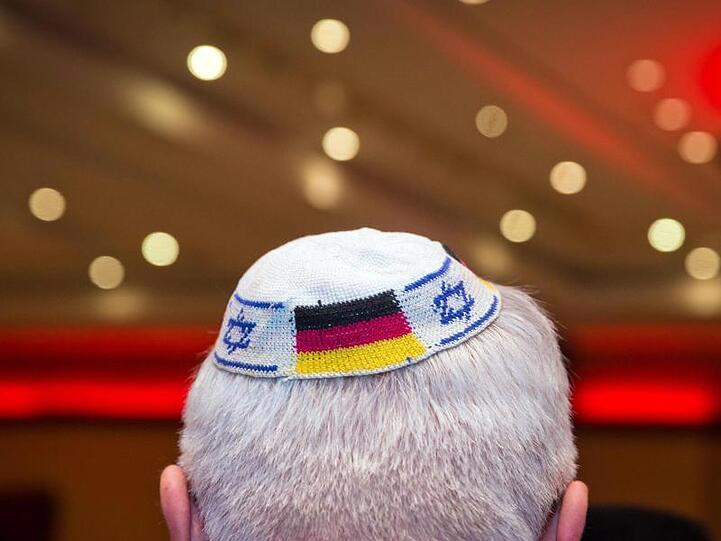Ein Mann trägt eine Kippa mit eingearbeiteten israelischen und deutschen Fahnen.