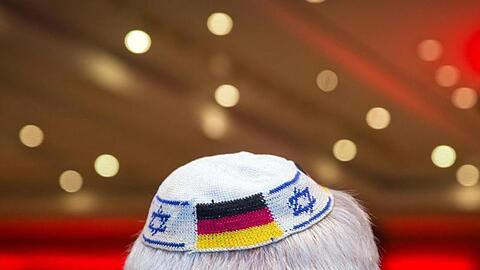 Ein Mann trägt eine Kippa mit eingearbeiteten israelischen und deutschen Fahnen.