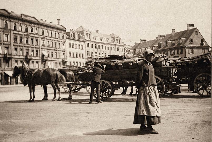 Ein Pferdewagen mit Brennholz für den Verkauf steht um 1890 am Isartorplatz. An der nahen Unteren Lände an der Isar lieferten Flöße die Stämme für die Bevölkerung an.