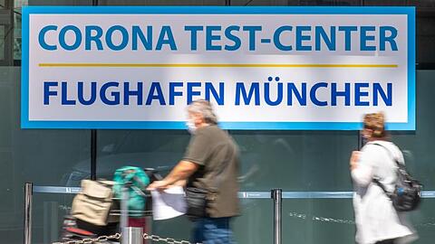 Reisende gehen zur Registration des Corona-Testzentrum am Münchner Flughafen. Foto: Peter Kneffel/dpa