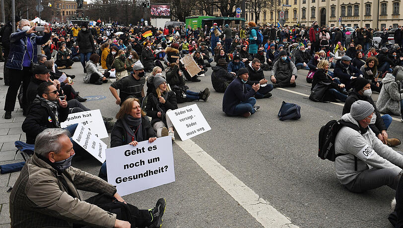 Teilnehmer der Demonstration gegen Maßnahmen der Bundesregierung zur Eindämmung der Corona-Ausbreitung sitzen vor dem Landtag und machen eine Sitzblockade.
