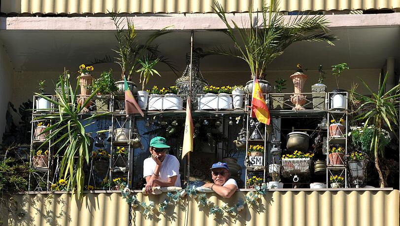Zwei Hobbygärtner und ihre Pflanzen genießen die Frühlingssonne auf ihrem Balkon.